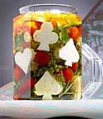 Variety of vegetables pickled with feta cheese, cherry tomatoes and herbs in glass jar