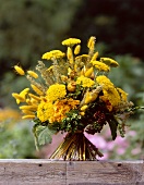 Close-up of yellow dry bouquet with buxus, immortelle, poppies and grass on wood