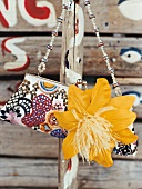 Close-up of playful embroidered purse with yellow flower hanging on bamboo