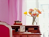 Flowers in glass jar on wooden desk with photo frame