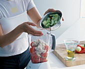 Filling blender with sliced vegetable - preparation of gazpacho
