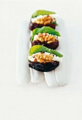 Dates with goat cheese, mint and walnuts on white background