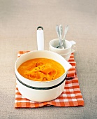 Carrot and mango soup garnished with coriander in casserole