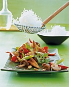 Crispy noodles with pieces of chicken and herbs on a plate