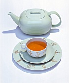 Designer tea cup, saucer and teapot on white background