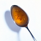 Close-up of spoon filled with yellow mustard sauce