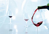 In ein Weinglas wird Rotwein eingeschenkt