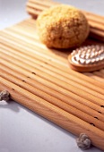 Close-up of brown sponge and massage brush placed on mat made of beech wood