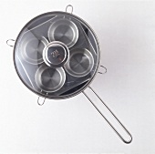 Brunch pan with lid and four small pans on white background, overhead view