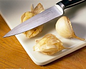 Cloves of garlic with a knife on cutting board