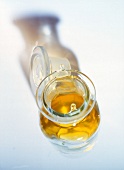 Close-up of glass carafe filled with sesame oil placed on white background