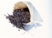 Close-up of dried lavender spilt out of white bag placed on white background