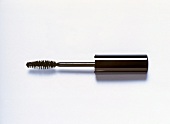 Close-up of mascara brush with black cover placed on white background