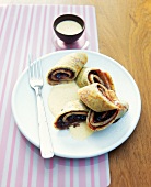 Five pancakes rolled poppy with fork on plate