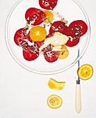 Carpaccio of beetroot, oranges and soft cheese on glass plate on white background