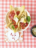 Penne chicory salad with cherry tomatoes, parma ham and basil in bowl