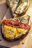 Close-up of toasted bread with eggplants and leeks on wooden board