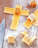 Ravioli dough with cooked teriyaki cubes and knife on wooden table