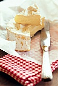Camembert cheese with knife on baking paper