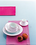 Coffee set consisting of cups, saucer plates and bowls on pink cloth
