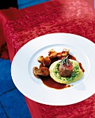 Rehmedaillon with porcini mushrooms and cabbage puree on red brocade table cloth