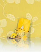 Yellow sandal, belt and handbag against yellow floral wallpaper