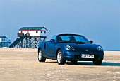 Convertible car on beach with lifeguard cabin in background