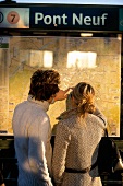 Rear view of couple looking at map in Pont Neuf Metro station, Paris, France