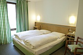 Bedroom with bed, cushion, chairs and curtains in hotel, Germany