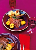 Roast goose, potato dumplings and mugwort on plate with a glass of red wine