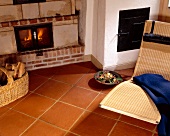 Living room with wicker lounger, fireplace and terracotta tiles