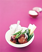 Lamb curry garnished with beans in bowl on pink background