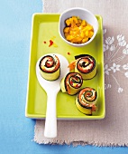 Zucchini rolls in green serving dish with bowl of mango dip
