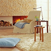 Wohnzimmer mit offenem Kamin Sessel und Wollteppich, winterlich