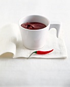 Chili chocolate mousse in white cup next to a chili pepper