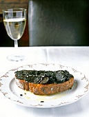 Bread with truffle slices on plate and glass of white wine