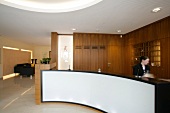 Receptionist standing at hotel reception counter in hotel, Germany