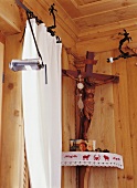 Herrgottswinkel mit Rosenkranz vor Wandvertäfelung aus Holz, Kreuz