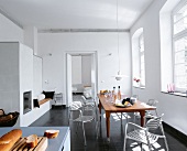 Eine weiße Wohnküche mit Kachelofen und langem Holztisch