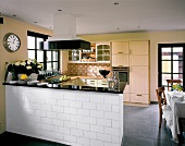 Beige fitted kitchen with bar counter and dining table