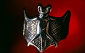 Close-up of silver bat ring against red background