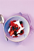 Bowl of dessert with fresh berries and cream, overhead view