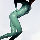 Nude woman's body covered with green mud