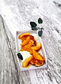 Goat cheese fritters with olive oil foam and peaches in serving dish