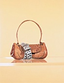 Shoulder bag with croco embossing wrapped with studded leather belt on glass shelf