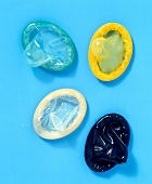 Four multi-coloured condoms on blue background