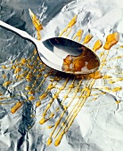 Caramel being spread on aluminium foil by spoon
