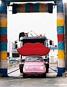 Fiat Cinquecento in pink, auf dem Dach Disignersofa "Bocca" vor LKW