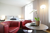 Room with bed, red sofa, table and flower pot at hotel in Switzerland