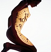 Nude woman with projector clock dial on her body kneeling, bending